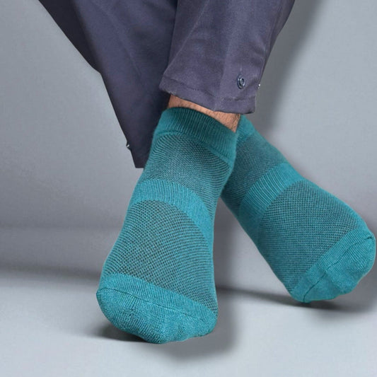 Teal socks worn with a dark blue pant on a neutral background