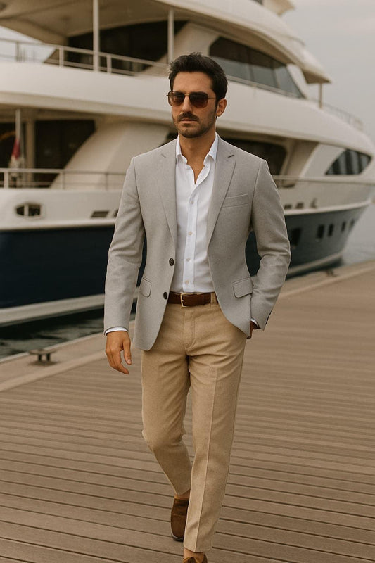 A well groomed man in grey jacket and beige pants coming from his yacht in the background 